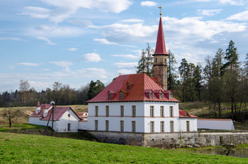 Ancient small castle with white walls and red roof. Sunny summer day, blue sky. 