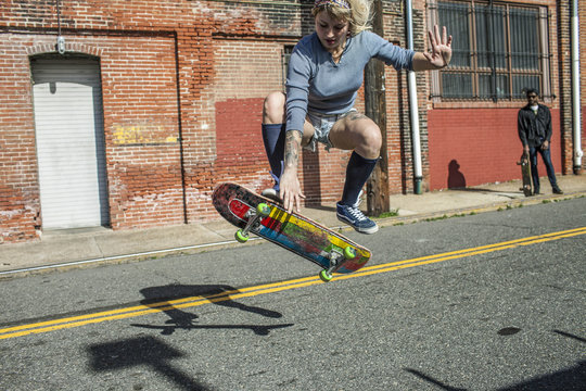 A young woman skateboarding on road