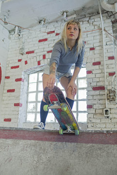 Young woman with skateboard standing at basement skate park