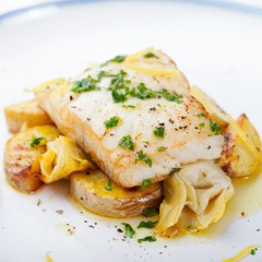 Roasted cod, codfish with baked potatoes and artichokes with lemon and herbs sauce