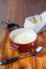 Potato cream-soup with chips and Basil pesto on wooden background