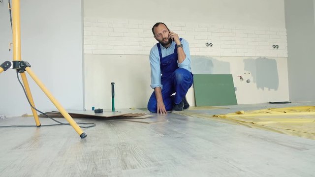 Male worker talking on cellphone while trying to install panels at new home
