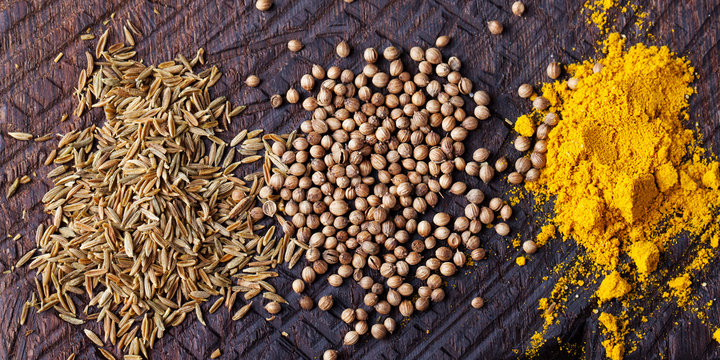 Assortment of spices. Cumin, carry, turmeric, coriander seeds on an old wooden cutting board