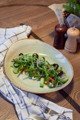 Salmon salad, cucumbers, olives, on a wooden table