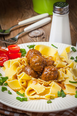Tagliatelle, meatballs in dark sauce and tomato.