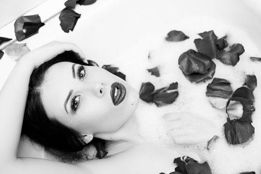 Black white photography of elegant sexy pretty girl with silk skin having fun laying in water bath relaxing 