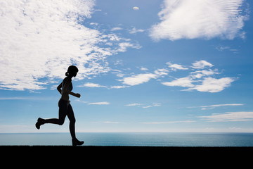 silhouette woman running on blue sky background