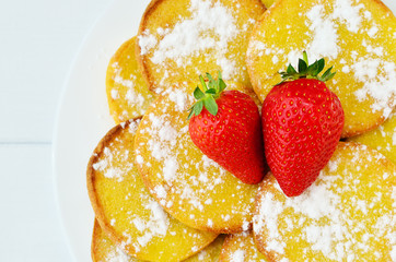 Pancakes with strawberries and powdered sugar close-up top view