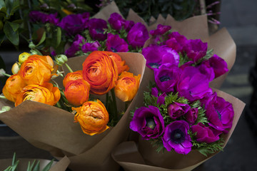set of violet anemone and orange ranunculus  flowers in bucket