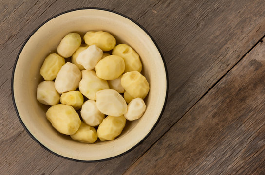 peeled raw potatoes in an enamel pot on the old boards. top view, close-up
