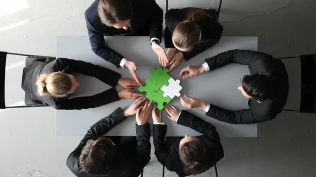 Group of business people assembling jigsaw puzzle and represent team support and help concept