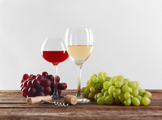 Wine and grape on wooden table against light background