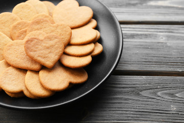 Heart shaped biscuits in black plate on wooden background