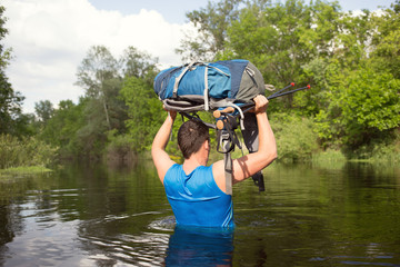 Man crossing the river with a backpack.