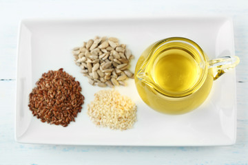 Different kinds of seeds and oil on wooden table
