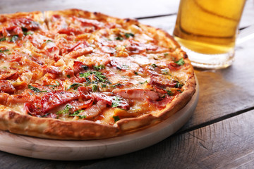 Tasty pizza and glass of beer are on wooden table, close up