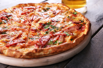 Tasty pizza and glass of beer are on wooden table, close up