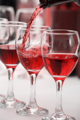 Red wine pouring into glasses, closeup