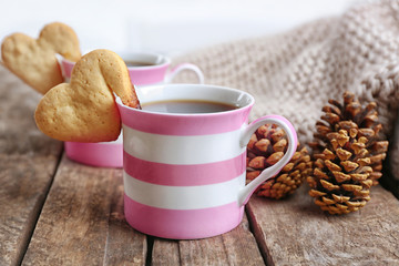 Heart shape cookie on cup of coffee on wooden table closeup