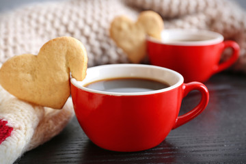 Heart shape cookie on cup of coffee on wooden table closeup