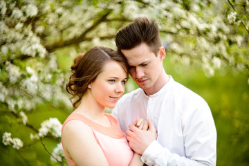 Couple in love under blooming branches spring day.