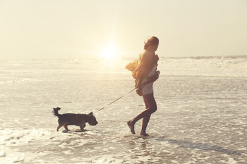 jolie femme senior active à la plage promenant son chien