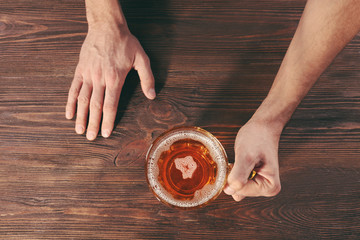 Fototapeta na wymiar Male hand holding glass of beer on wooden background