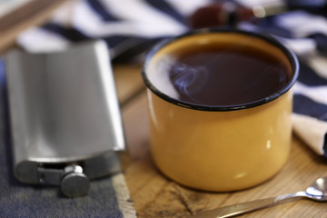 Cup of strong coffee with a flask on a wooden table, close up