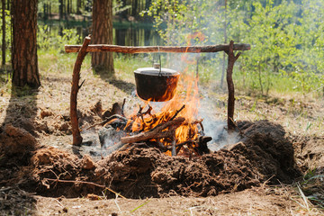 The fire near the camp. Cooking food on a fire. Journey into the wild concept.
