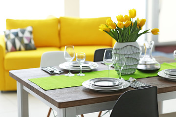 Dining room interior with sofa and table served for dinner