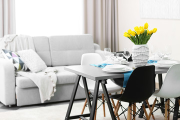 Dining room interior with sofa and table served for dinner