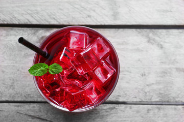 Glass of cherry soda with ice and fresh mint on rustic wooden background © Africa Studio
