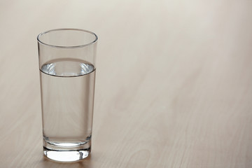 Glass of pure water on light wooden table