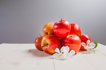 some apples on a white wooden surface with flowers