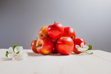 red apples on a white wood table with flowers