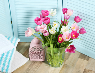 Bouquet of beautiful tulips in glass vase on floor