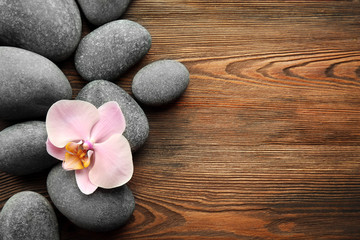 Obraz na płótnie Canvas Spa stones and orchid flower on wooden background