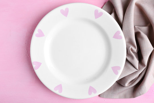 Empty plate and napkin on pink background