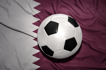 black and white football ball on the national flag of qatar