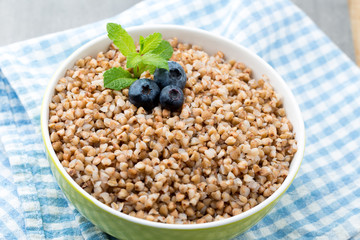 Buckwheat porridge in a bowl with mint leaves and blueberries.