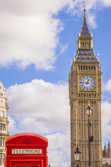 Fototapeta na wymiar Iconic Red British telephone box with Big Ben on a sunny afternoon with blue sky and clouds - London, UK