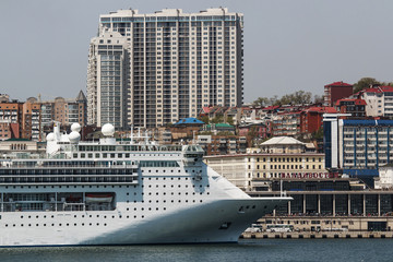 Obraz premium white cruise liner on a background of city buildings