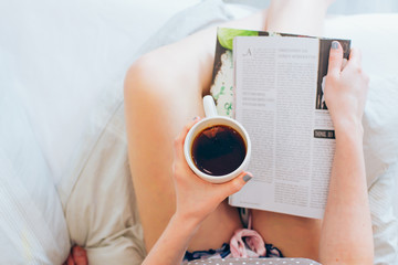 
Junge Frau liegt im Bett und liest Zeitschrift