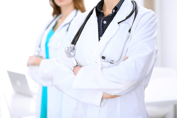 Close up of unknown female doctor standing in a hospital with her colleague in the background