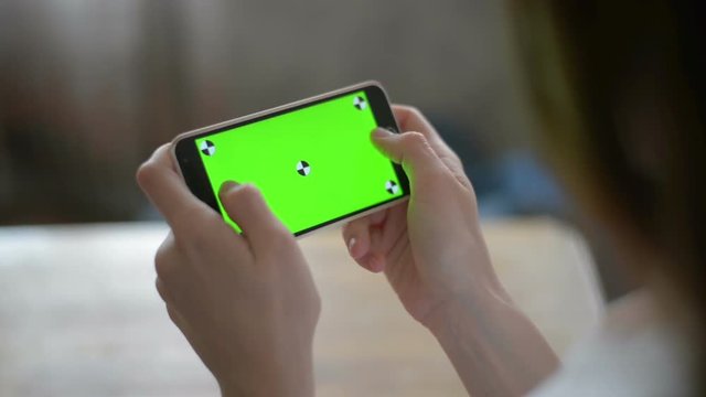 Young Girl is Holding Smartphone with Green Screen at Evening Time.