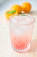 Fresh orange cocktail with ice and mint on a wooden board .