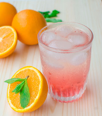 Fresh orange cocktail with ice and mint on a wooden board .