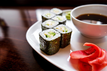 Rolls in nori seaweed with avocado, pickled ginger and soy sauce. Asian cuisine, traditional dish - sushi.