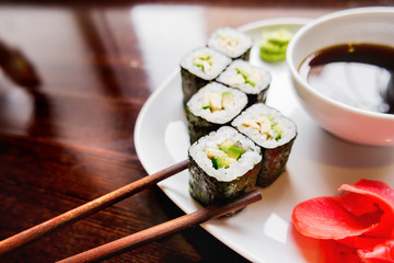 Rolls in nori seaweed with avocado, pickled ginger and soy sauce. Asian cuisine, traditional dish - sushi.
