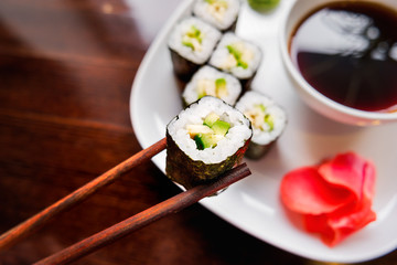 Rolls in nori seaweed with avocado, pickled ginger and soy sauce. Asian cuisine, traditional dish - sushi.